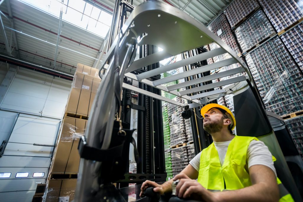 Warehouse worker in a forklift truck places the packages on the shelves